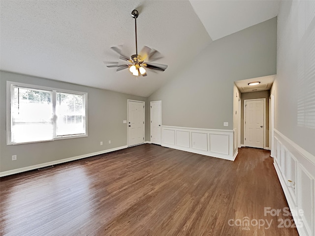 120 Todd Dr NW, Concord, NC 28025 - unfurnished living room featuring dark wood-type flooring, a ceiling fan, high vaulted ceiling, a wainscoted wall, and a decorative wall