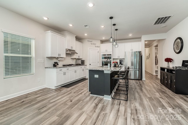 9274 Dunwich Dr, Gastonia, NC 28056 - kitchen featuring stainless steel appliances, under cabinet range hood, white cabinetry, light wood-type flooring, and recessed lighting
