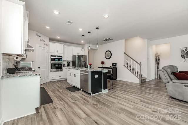 9274 Dunwich Dr, Gastonia, NC 28056 - kitchen featuring appliances with stainless steel finishes, open floor plan, light wood-style flooring, white cabinetry, and recessed lighting