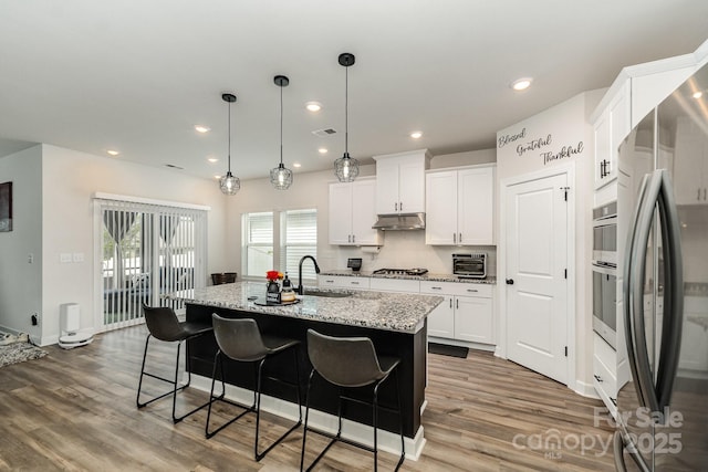 9274 Dunwich Dr, Gastonia, NC 28056 - kitchen featuring stainless steel appliances, a sink, under cabinet range hood, wood finished floors, and recessed lighting