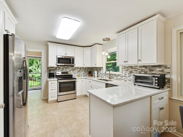 13617 Lake Bluff Dr, Matthews, NC 28105 - kitchen featuring appliances with stainless steel finishes, a sink, a peninsula, decorative backsplash, and plenty of natural light
