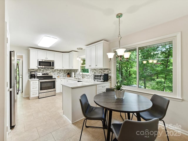 13617 Lake Bluff Dr, Matthews, NC 28105 - kitchen with appliances with stainless steel finishes, backsplash, light countertops, light tile patterned floors, and white cabinets