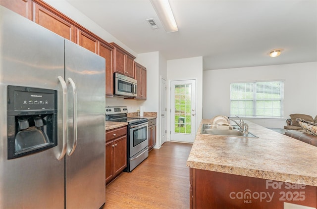 8953 Bradstreet Commons Way, Charlotte, NC 28215 - kitchen featuring appliances with stainless steel finishes, light wood-style flooring, light countertops, brown cabinets, and open floor plan