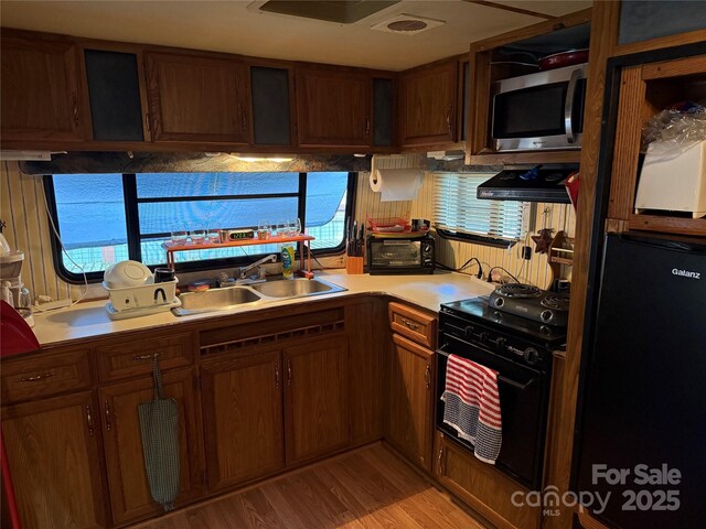160/162 Arrowood Trl Unit F28/F29, Mount Gilead, NC 27306 - kitchen with black appliances, a sink, light countertops, light wood-style flooring, and exhaust hood