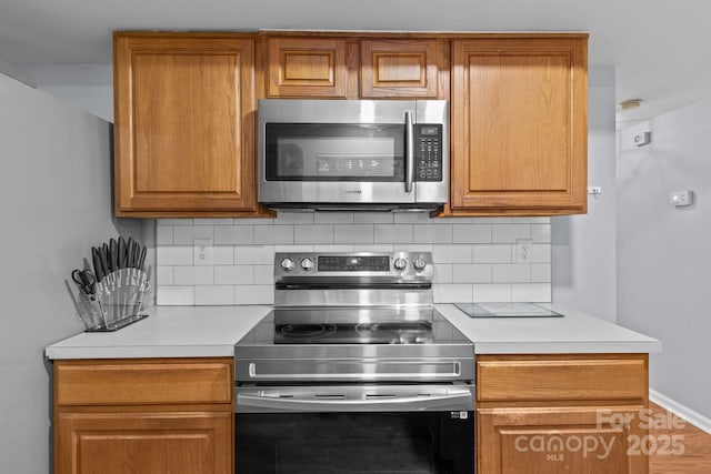 7212 Morsey Ct, Charlotte, NC 28269 - kitchen featuring stainless steel appliances, backsplash, light countertops, and brown cabinetry