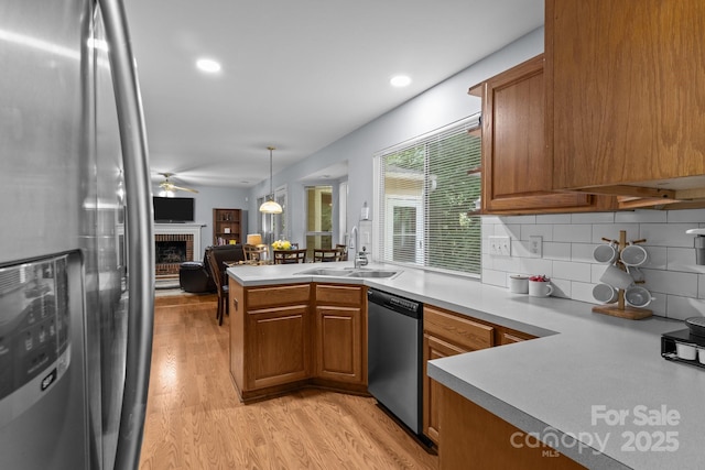 7212 Morsey Ct, Charlotte, NC 28269 - kitchen with stainless steel appliances, a sink, brown cabinetry, light wood finished floors, and a peninsula