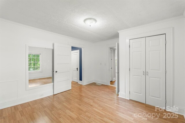 202 Glenn Ave, Kannapolis, NC 28081 - unfurnished bedroom with crown molding, light wood finished floors, a closet, and a textured ceiling