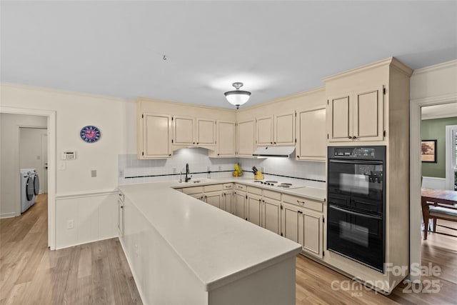 2917 Rustic Ln, Charlotte, NC 28210 - kitchen featuring washing machine and clothes dryer, under cabinet range hood, light wood finished floors, a peninsula, and crown molding