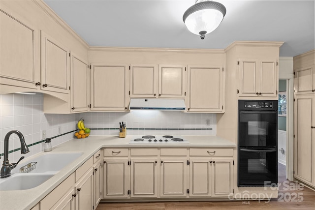 2917 Rustic Ln, Charlotte, NC 28210 - kitchen featuring white electric cooktop, under cabinet range hood, cream cabinets, and backsplash