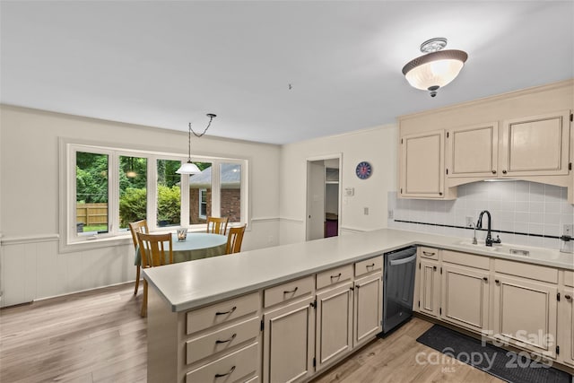 2917 Rustic Ln, Charlotte, NC 28210 - kitchen with dishwashing machine, a peninsula, light countertops, light wood-style flooring, and wainscoting