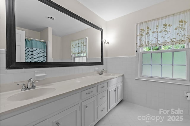 2917 Rustic Ln, Charlotte, NC 28210 - bathroom with tile walls, double vanity, tile patterned flooring, and a wainscoted wall