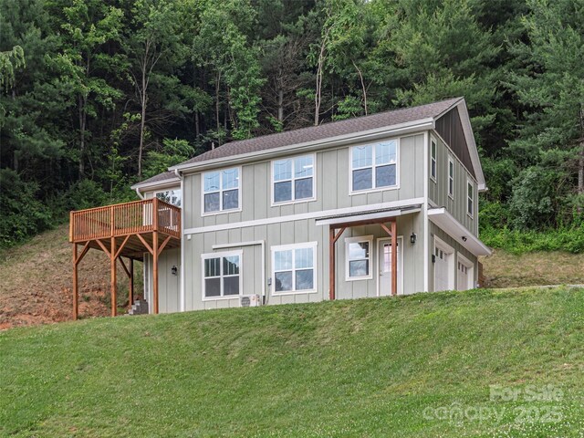558 Liner Cove Rd, Waynesville, NC 28786 - view of front of house featuring an attached garage, board and batten siding, a front yard, a wooden deck, and a forest view