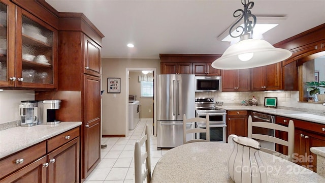 1695 Arden Dr, Lincolnton, NC 28092 - kitchen featuring stainless steel appliances, washer and dryer, backsplash, light tile patterned floors, and decorative light fixtures