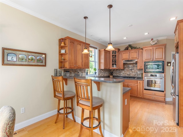 80 Feather Ln, Waynesville, NC 28786 - kitchen with appliances with stainless steel finishes, a peninsula, a kitchen bar, brown cabinetry, and backsplash