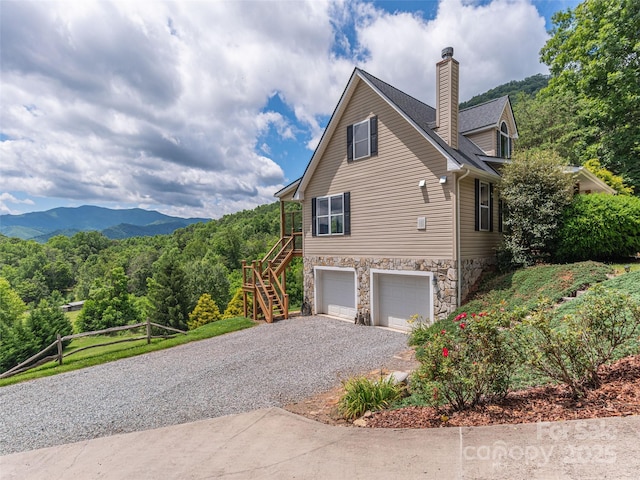 80 Feather Ln, Waynesville, NC 28786 - view of side of home featuring stairway, gravel driveway, an attached garage, stone siding, and a chimney