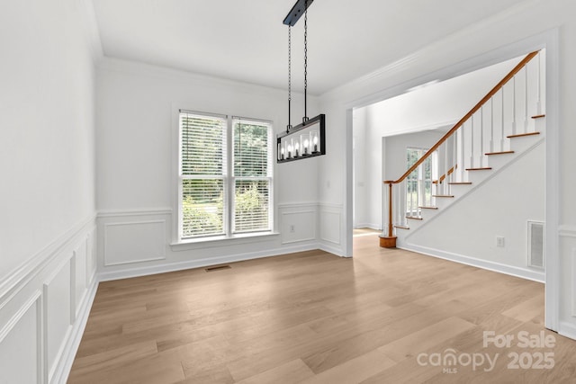 15400 Groveland St, Huntersville, NC 28078 - unfurnished dining area featuring light wood finished floors, a wainscoted wall, stairway, ornamental molding, and a decorative wall