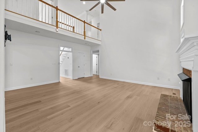 15400 Groveland St, Huntersville, NC 28078 - unfurnished living room with a towering ceiling, a fireplace, ceiling fan, stairway, and light wood-style floors