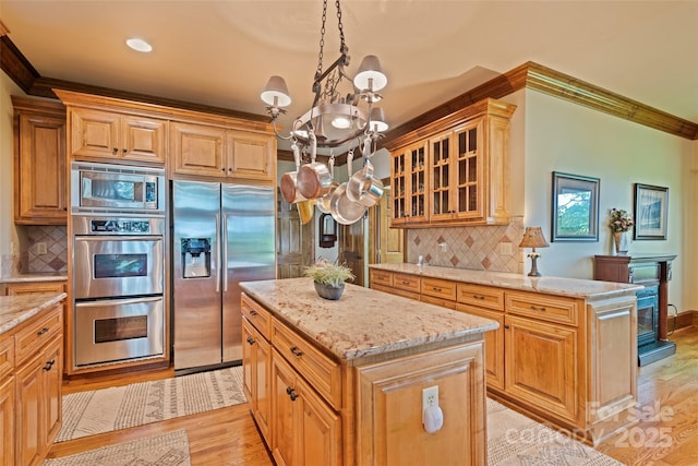 102 Coyote Rdg, Maggie Valley, NC 28751 - kitchen with appliances with stainless steel finishes, a kitchen island, a chandelier, light wood-style floors, and ornamental molding