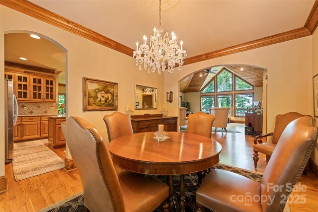 102 Coyote Rdg, Maggie Valley, NC 28751 - dining room featuring arched walkways, light wood-style floors, ornamental molding, a ceiling fan, and lofted ceiling