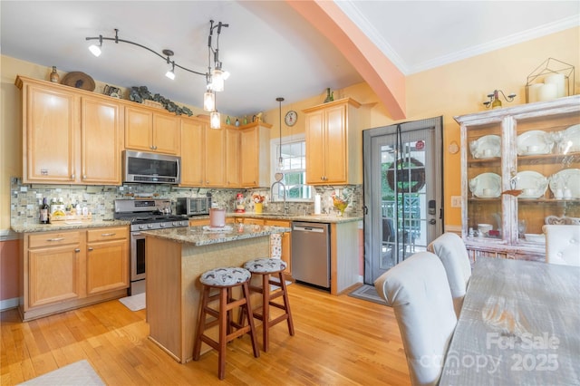 333 Garden Valley Dr, Winston Salem, NC 27107 - kitchen featuring appliances with stainless steel finishes, arched walkways, a center island, light stone countertops, and light wood finished floors