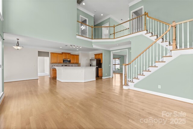 112 Doyle Farm Ln, Mooresville, NC 28115 - unfurnished living room with crown molding, a high ceiling, light wood-style flooring, baseboards, and stairway