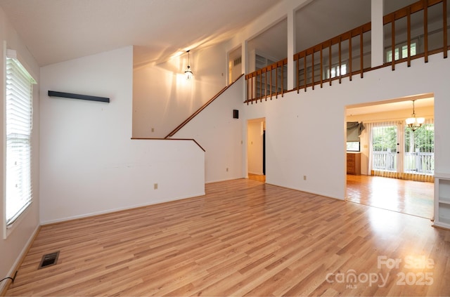 3221 5th Street Ct NW, Hickory, NC 28601 - unfurnished living room featuring wood finished floors, a chandelier, baseboards, and a high ceiling