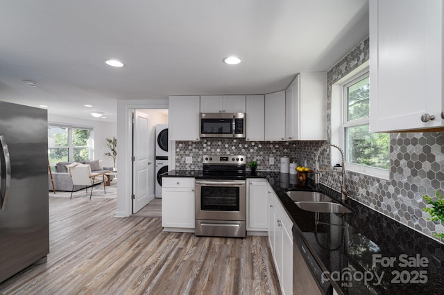1212 Frank Ext, Rock Hill, SC 29730 - kitchen featuring stainless steel appliances, stacked washing machine and dryer, a sink, white cabinetry, and tasteful backsplash