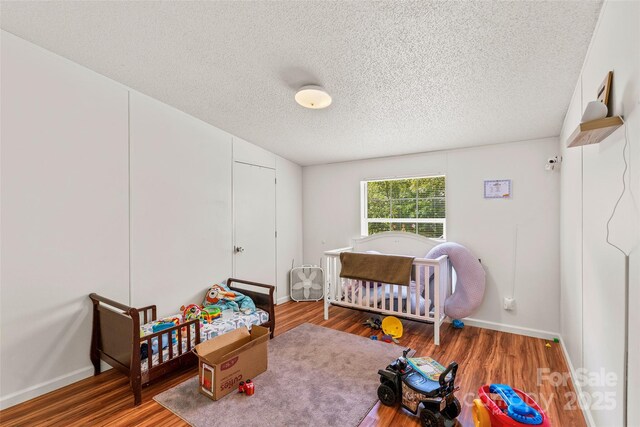 14 Luckenbach Dr, Fairview, NC 28730 - bedroom featuring a textured ceiling, wood finished floors, baseboards, and a nursery area