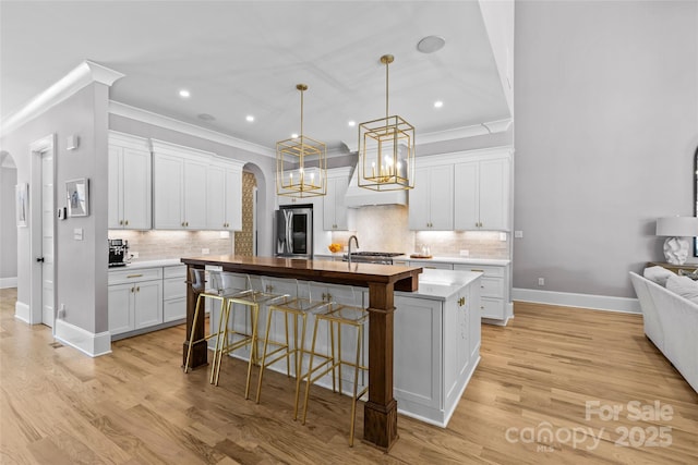 5638 Timber Ln, Charlotte, NC 28270 - kitchen featuring arched walkways, a kitchen island with sink, a kitchen bar, stainless steel fridge, and backsplash