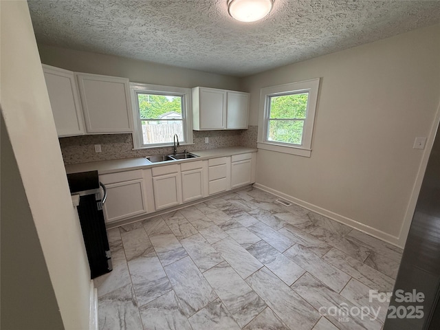 322 Buffalo St, Shelby, NC 28150 - kitchen featuring stove, plenty of natural light, decorative backsplash, white cabinetry, and a textured ceiling