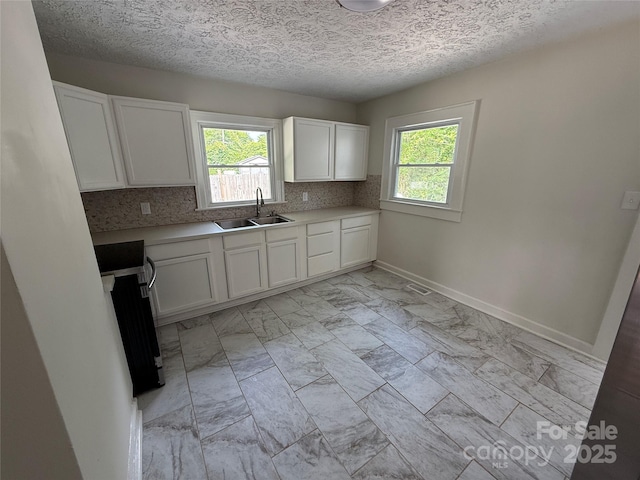 322 Buffalo St, Shelby, NC 28150 - kitchen with range, light marble finish flooring, white cabinetry, light countertops, and backsplash