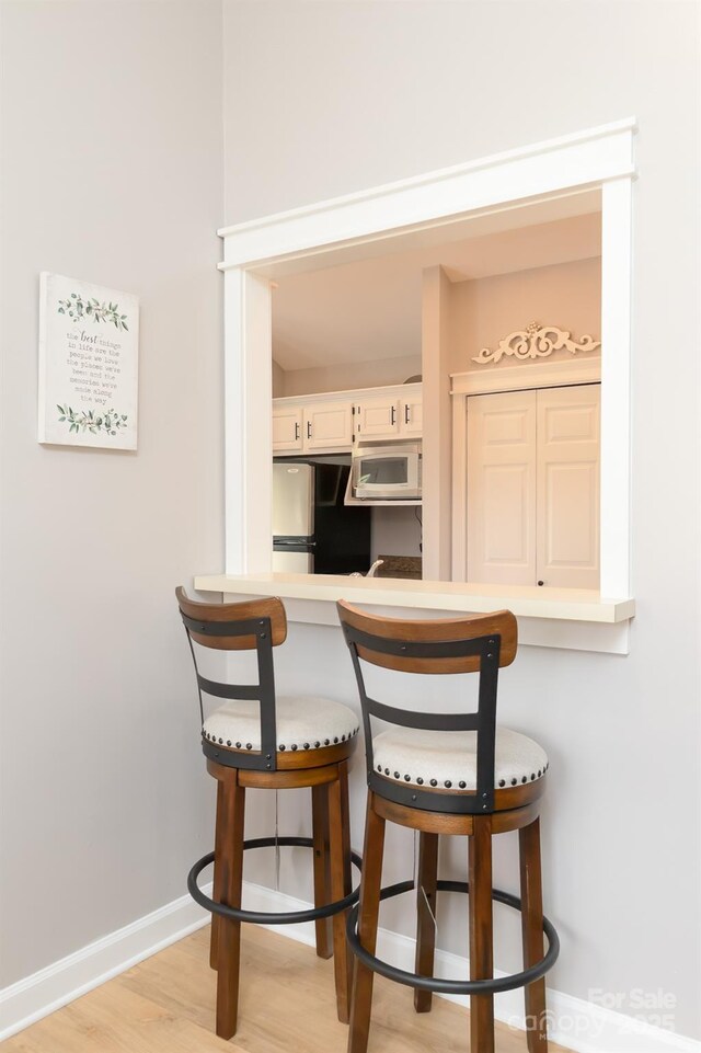 100 Donna Dr, Franklin, NC 28734 - kitchen featuring freestanding refrigerator, a kitchen breakfast bar, white microwave, white cabinets, and light countertops