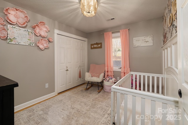 100 Donna Dr, Franklin, NC 28734 - bedroom with a closet, a crib, wood finished floors, a chandelier, and a textured ceiling