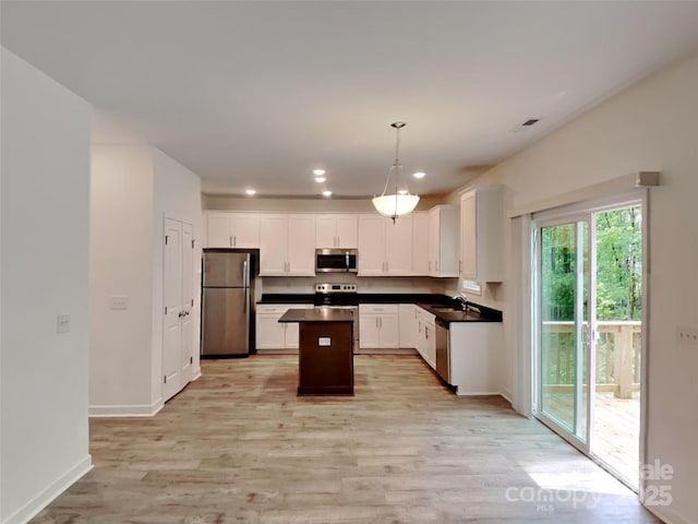 2612 Cold Springs Rd, Concord, NC 28025 - kitchen with stainless steel appliances, light wood finished floors, dark countertops, white cabinets, and a center island