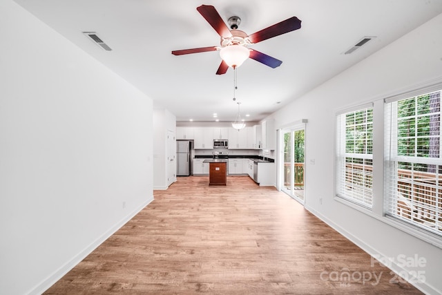 2612 Cold Springs Rd, Concord, NC 28025 - kitchen with stainless steel appliances, dark countertops, light wood-type flooring, open floor plan, and white cabinets