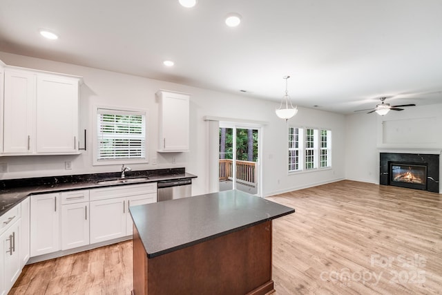 2612 Cold Springs Rd, Concord, NC 28025 - kitchen featuring dark countertops, dishwasher, ceiling fan, light wood-type flooring, and a glass covered fireplace