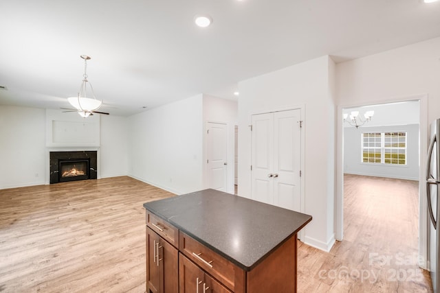 2612 Cold Springs Rd, Concord, NC 28025 - kitchen featuring dark countertops, light wood-type flooring, a kitchen island, a glass covered fireplace, and recessed lighting