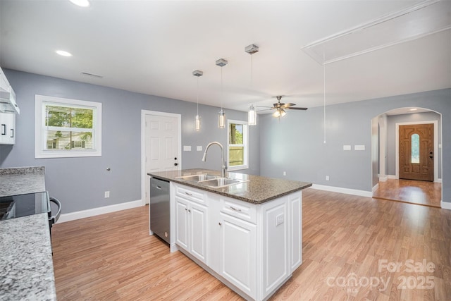 952 Salisbury St, Wadesboro, NC 28170 - kitchen with appliances with stainless steel finishes, arched walkways, light wood-type flooring, an island with sink, and white cabinetry