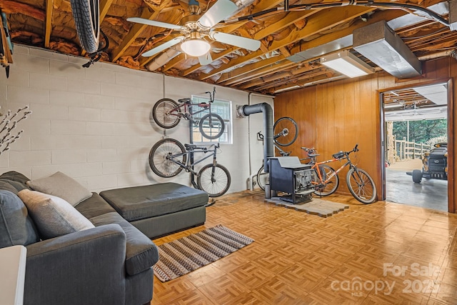 362 Mills Gap Rd Unit 5, Asheville, NC 28803 - basement featuring a wood stove, a ceiling fan, wooden walls, and concrete block wall