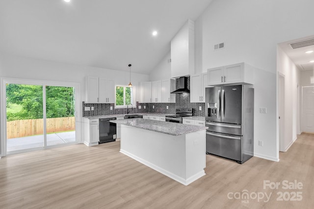 516 N Mulberry St, Cherryville, NC 28021 - kitchen featuring appliances with stainless steel finishes, wall chimney exhaust hood, a center island, tasteful backsplash, and light wood-style floors