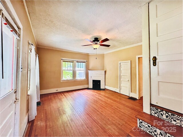 602 Brookshire St, Asheville, NC 28803 - unfurnished living room with ornamental molding, baseboards, hardwood / wood-style flooring, a brick fireplace, and a ceiling fan