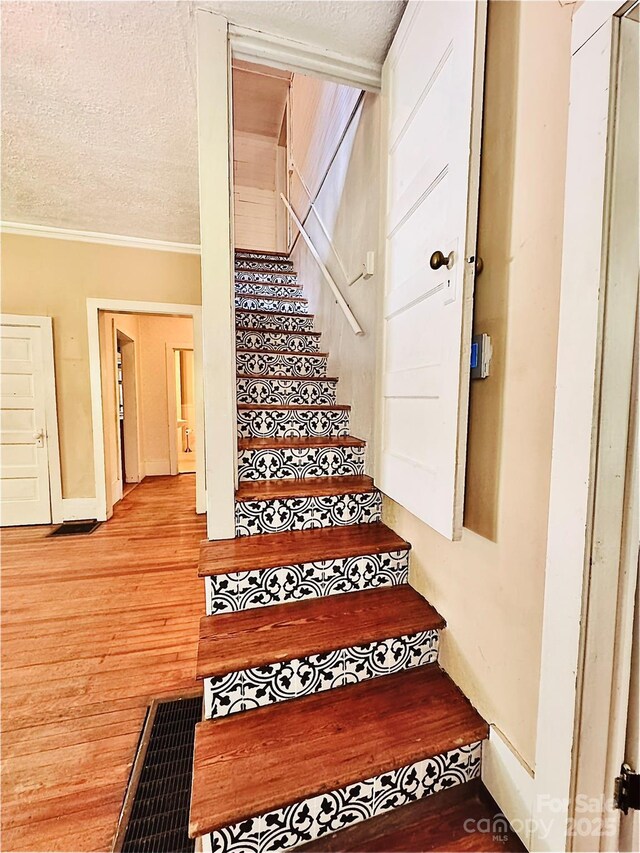 602 Brookshire St, Asheville, NC 28803 - stairway featuring wood finished floors, crown molding, and a textured ceiling