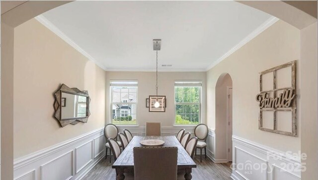 2009 Trindle Vine Ln, Waxhaw, NC 28173 - dining space with wood finished floors, crown molding, a wainscoted wall, arched walkways, and a decorative wall