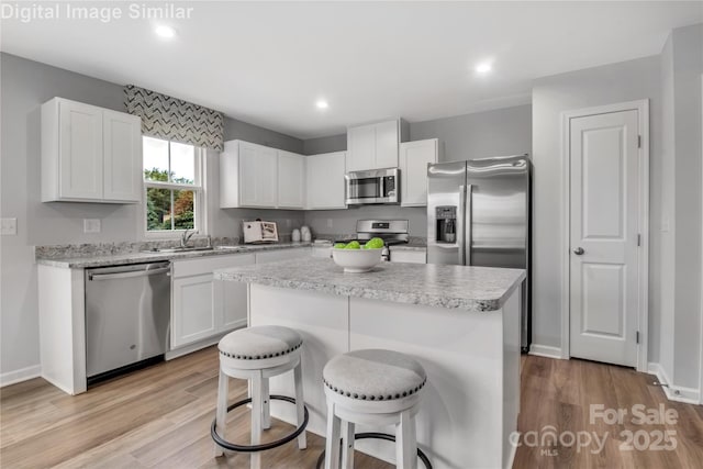 5995 Granbury Dr, Kannapolis, NC 28081 - kitchen featuring stainless steel appliances, a sink, a breakfast bar, light wood-style floors, and light countertops