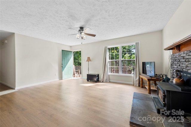 55 Gilbert B Crook Rd, Candler, NC 28715 - living room featuring a wood stove, ceiling fan, plenty of natural light, wood finished floors, and a textured ceiling
