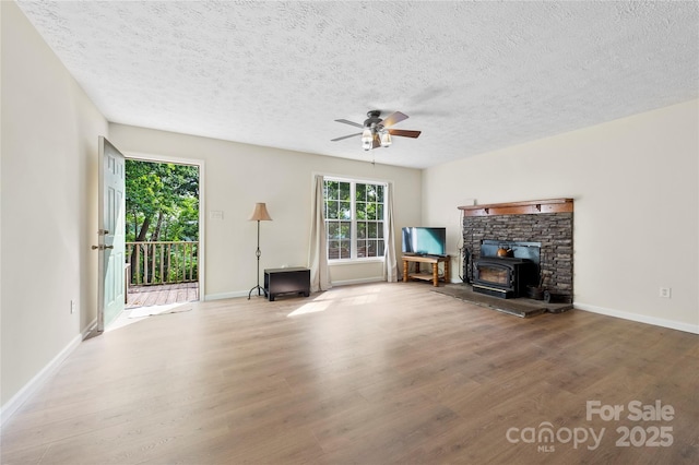 55 Gilbert B Crook Rd, Candler, NC 28715 - unfurnished living room featuring wood finished floors, a ceiling fan, a wood stove, and a textured ceiling