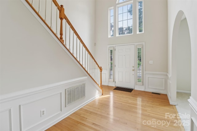 2321 Oberwood Dr, Charlotte, NC 28270 - entrance foyer with arched walkways, stairs, a wainscoted wall, wood finished floors, and a decorative wall
