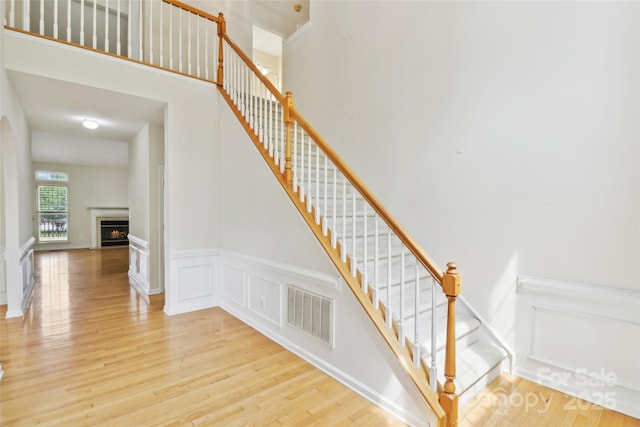 2321 Oberwood Dr, Charlotte, NC 28270 - staircase with wood finished floors, a decorative wall, a wainscoted wall, and a lit fireplace