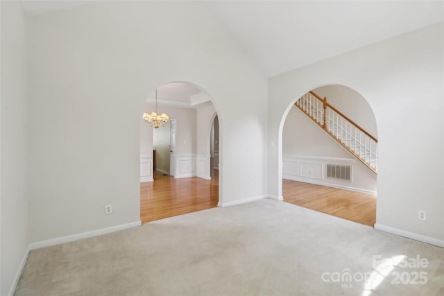 2321 Oberwood Dr, Charlotte, NC 28270 - empty room with carpet floors, a chandelier, arched walkways, a decorative wall, and wainscoting