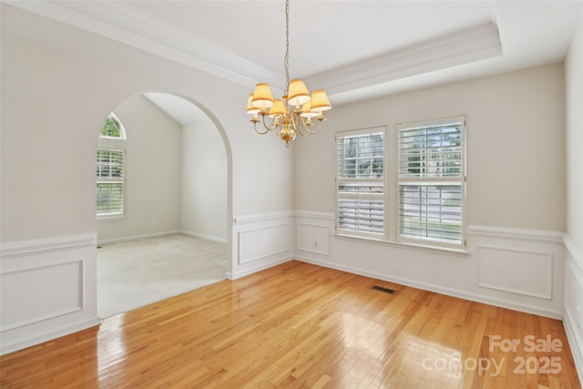 2321 Oberwood Dr, Charlotte, NC 28270 - empty room featuring light wood-style flooring, a chandelier, a wainscoted wall, ornamental molding, and arched walkways